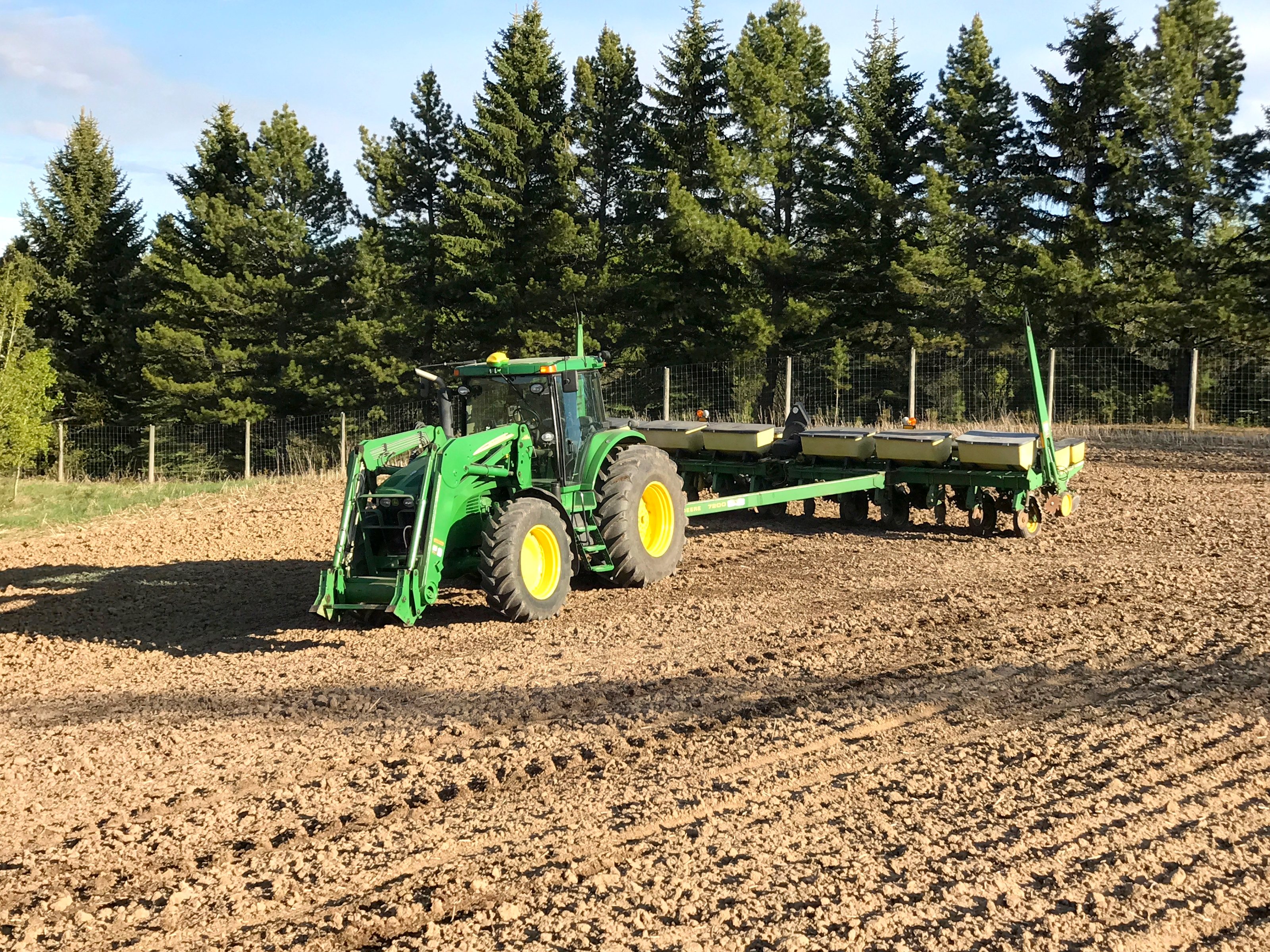 A John Deere tractor and planter on tilled ground in spring