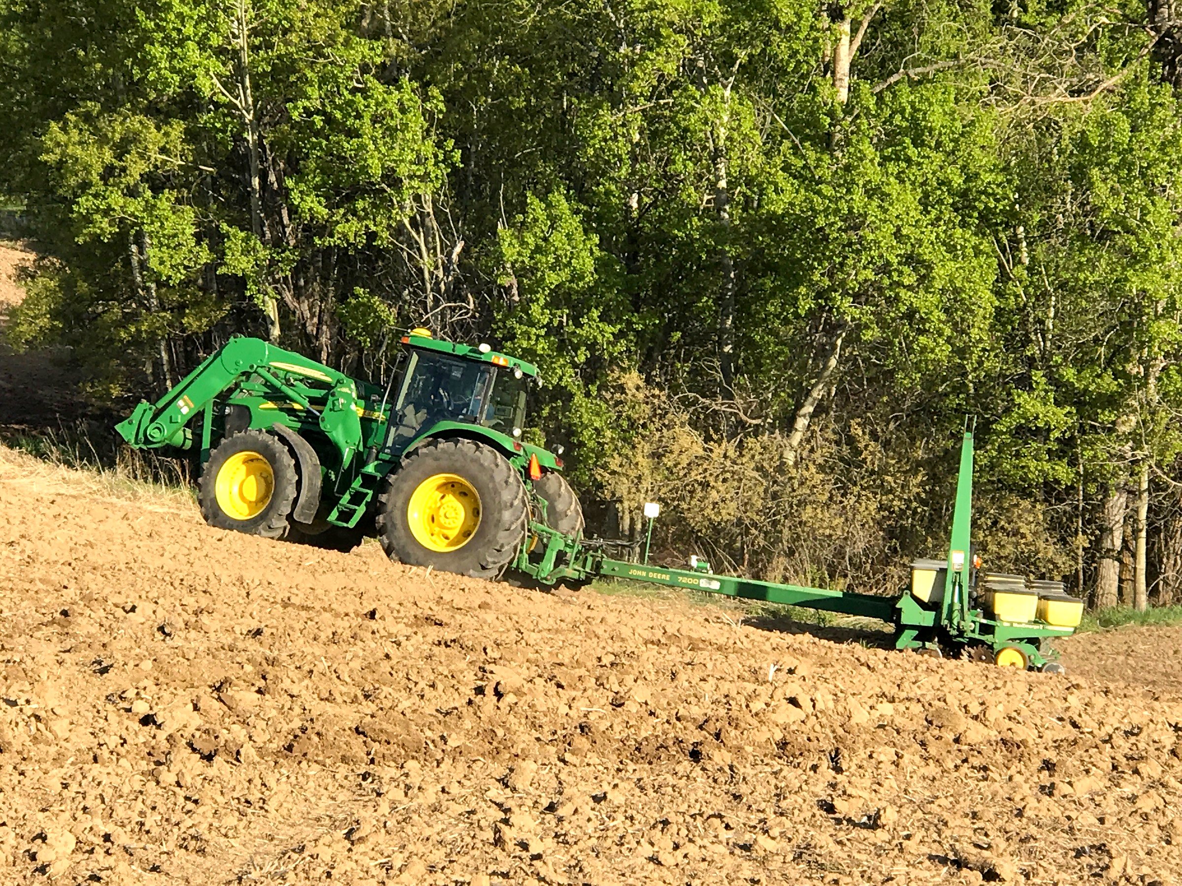 A John Deere tractor and planter at the treeline