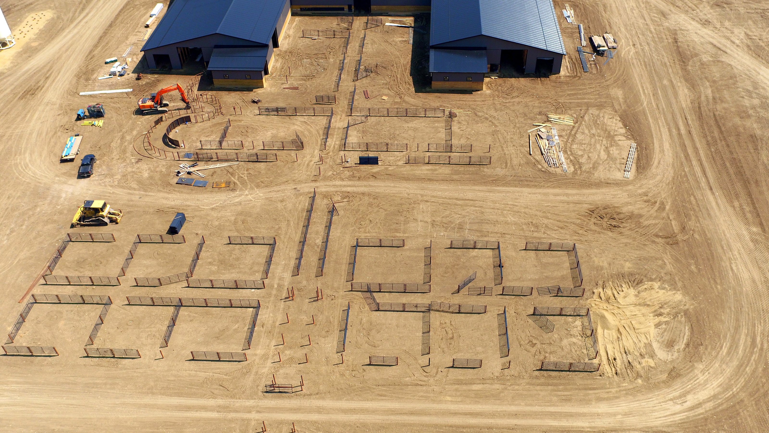 Building the feedlot pens, an excavator and a loader at work, from the air