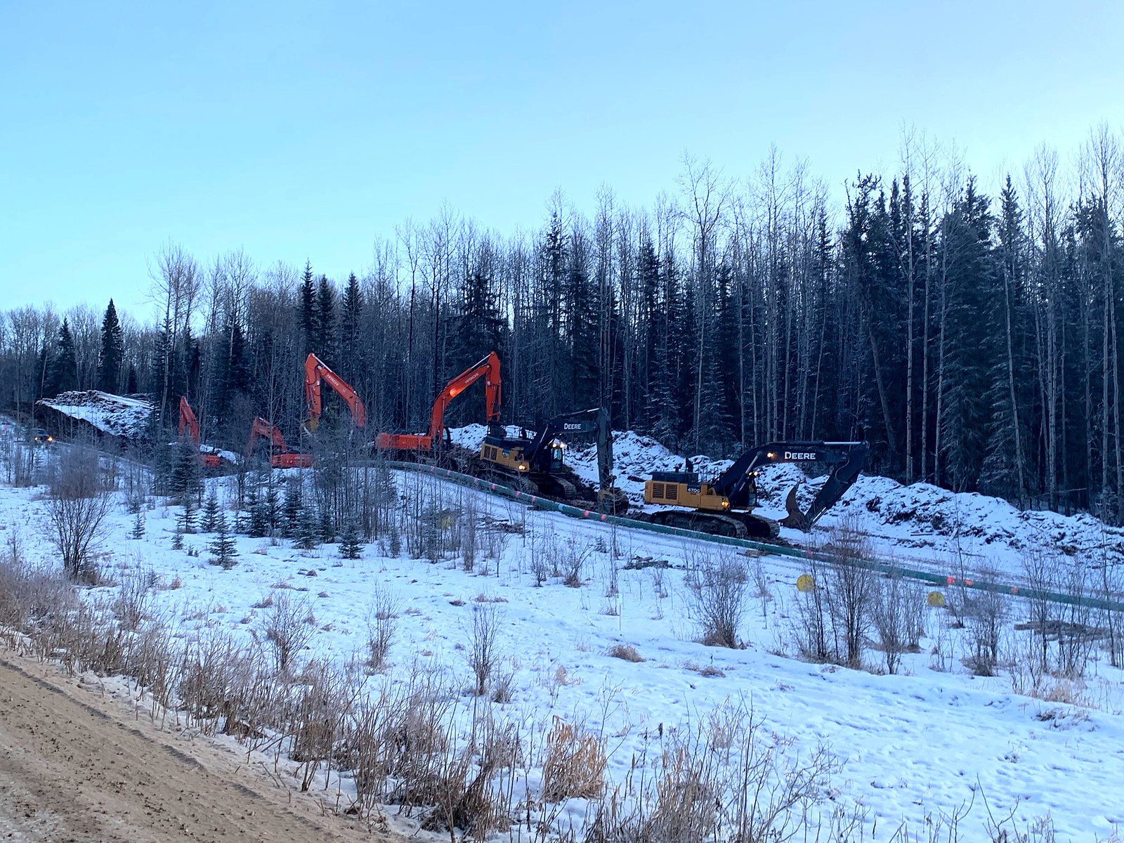 Excavators at work on a winter right-of-way at dusk, with the perception overlay